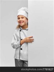 cooking, culinary and profession concept - happy smiling little girl in chef’s toque and jacket with white board over grey background. happy little girl in chef’s toque with white board