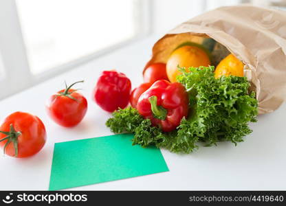 cooking, diet, vegetarian food and healthy eating concept - close up of paper bag with fresh ripe juicy vegetables and greens on kitchen table at home