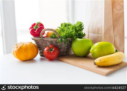 cooking, diet, vegetarian food and healthy eating concept - close up of basket with fresh ripe juicy vegetables, greens and fruits on kitchen table at home