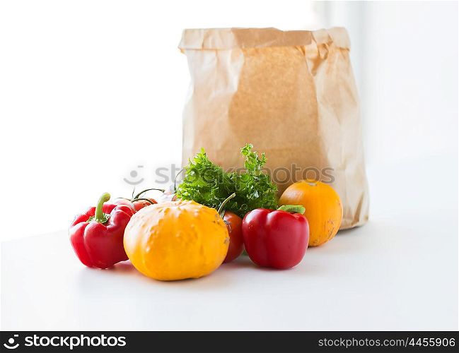 cooking, diet, vegetarian food and healthy eating concept - close up of paper bag with fresh ripe juicy vegetables, greens and fruits on kitchen table at home