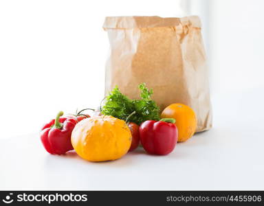 cooking, diet, vegetarian food and healthy eating concept - close up of paper bag with fresh ripe juicy vegetables, greens and fruits on kitchen table at home