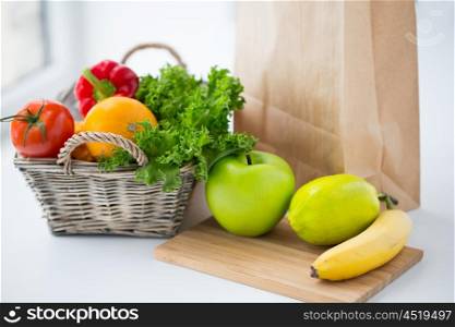cooking, diet, vegetarian food and healthy eating concept - close up of basket with fresh ripe juicy vegetables, greens and fruits on kitchen table at home