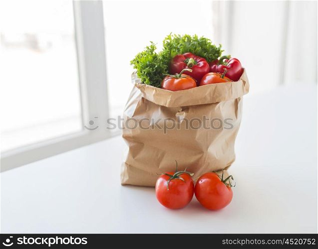 cooking, diet, vegetarian food and healthy eating concept - close up of paper bag with fresh ripe juicy vegetables and greens on kitchen table at home