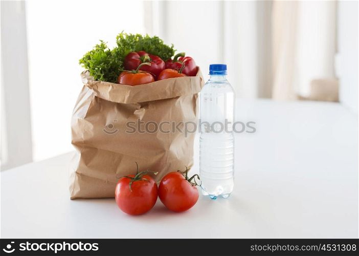 cooking, diet, vegetarian food and healthy eating concept - close up of paper bag with fresh ripe juicy vegetables and water bottle on kitchen table at home