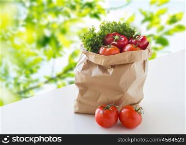 cooking, diet, vegetarian food and healthy eating concept - paper bag with fresh ripe juicy vegetables and greens on table over green natural background
