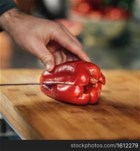Cooking dinner. Chef holding a knife and cutting red bell pepper, close-up. Cooking dinner - Chef Holding a Knife and Cutting Red Bell Pepper