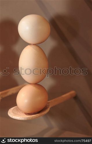 Cooking Eggs: Three Eggs in Vertical Position on Wooden Spoon