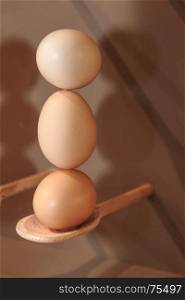 Cooking Eggs: Three Eggs in Vertical Position on Wooden Spoon