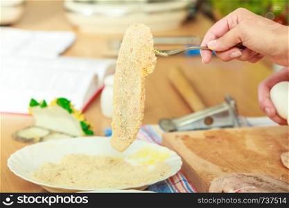 Cooking. Female hand preparing meal of breaded chicken cutlets, rolled raw chops in breadcrumbs