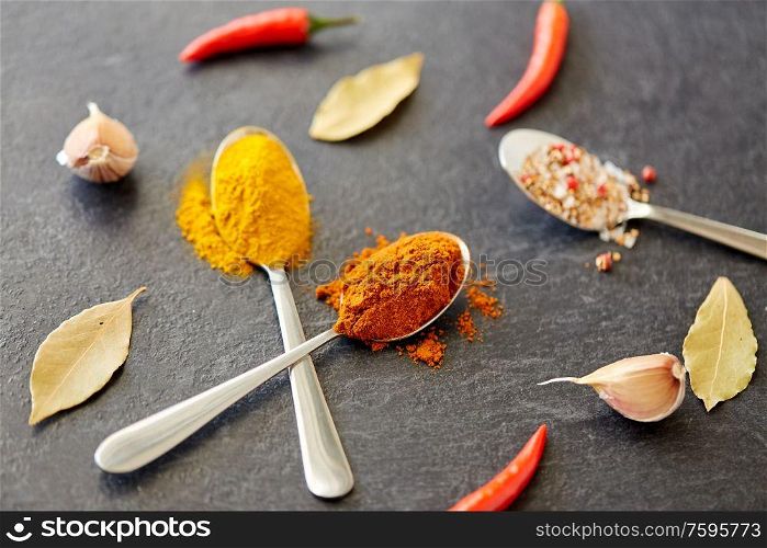 cooking, food and culinary concept - chili pepper on stone surface. spices, chili pepper, bay leaf and garlic on stone