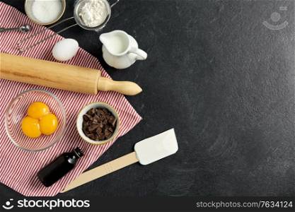 cooking food and culinary concept - rolling pin, milk, eggs, flour and chocolate on table. rolling pin, milk, eggs, flour and chocolate