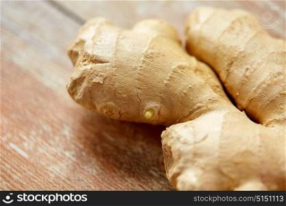 cooking, food and ethnoscience concept - close up of ginger root on wooden table. close up of ginger root on wooden table