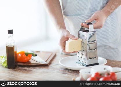 cooking, food and home concept - close up of male hands grating cheese