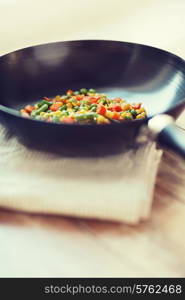 cooking, food and home concept - close up of wok pan with vegetables