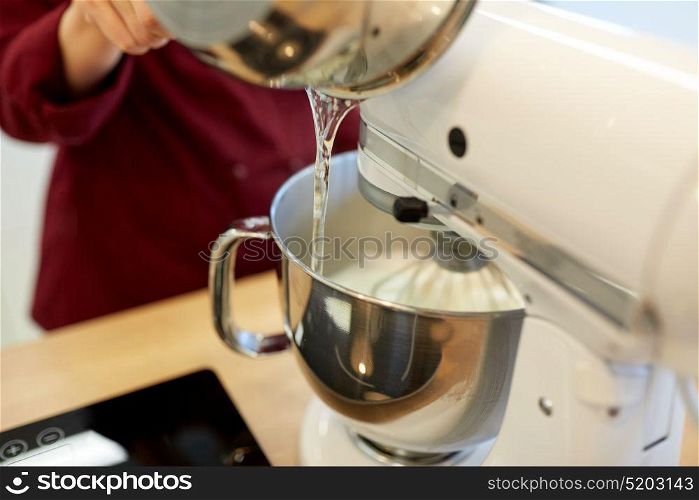 cooking, food and kitchen appliances concept - chef pouring ingredient from pot into electric mixer bowl. chef pouring ingredient from pot into mixer bowl