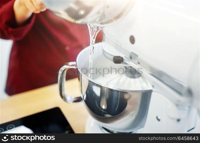 cooking, food and kitchen appliances concept - chef pouring ingredient from pot into electric mixer bowl. chef pouring ingredient from pot into mixer bowl