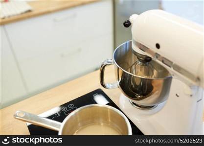 cooking, food and kitchen appliances concept - electric mixer and pot on stove. electric mixer and pot on stove at kitchen