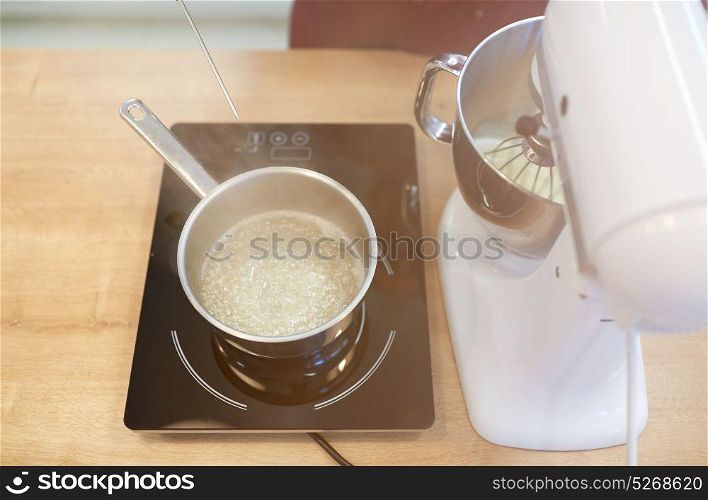 cooking, food and kitchen appliances concept - electric mixer and pot on stove. electric mixer and pot on stove at kitchen