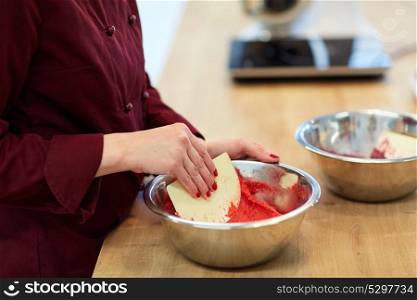 cooking, food and people concept - chef with spatula stirring macaron batter in bowl at pastry shop. chef making macaron batter at confectionery