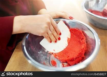 cooking, food and people concept - chef with spatula stirring macaron batter or cream in bowl at pastry shop. chef making macaron batter at confectionery