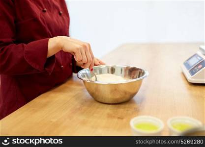 cooking food, baking and people concept - chef with flour in bowl making batter or dough. chef with flour in bowl making batter or dough