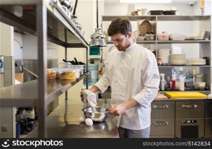 cooking food, baking and people concept - happy male chef cook with eggs pouring flour into bowl at restaurant or bakery kitchen. happy male chef cooking food at restaurant kitchen