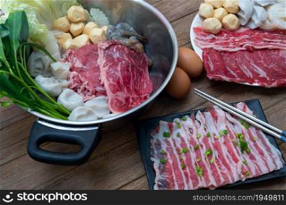 Cooking food by put a flesh beef, pork, egg and vegetable in to a hot pot for make a sukiyaki or shabu at japanese shabu buffet restaurant. Cooking food in hot pot for make sukiyaki or shabu