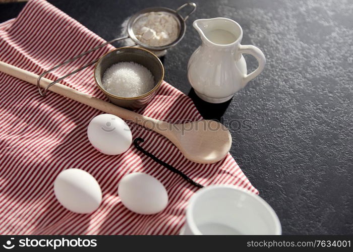 cooking food, culinary and recipe concept - eggs, milk, flour, wooden spoon and vanilla extract on table. eggs, sugar, milk, flour, spoon and vanilla