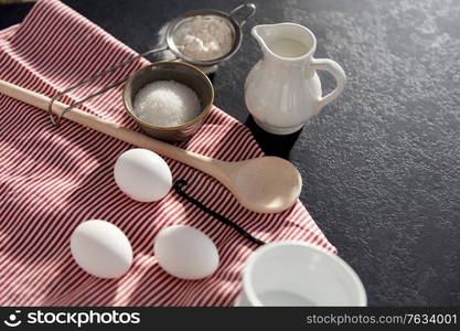 cooking food, culinary and recipe concept - eggs, milk, flour, wooden spoon and vanilla extract on table. eggs, sugar, milk, flour, spoon and vanilla