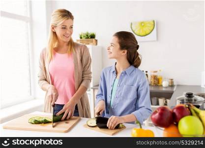 cooking food, family and people concept - happy mother and daughter chopping vegetables for dinner at home kitchen. happy family cooking vegetables at home kitchen