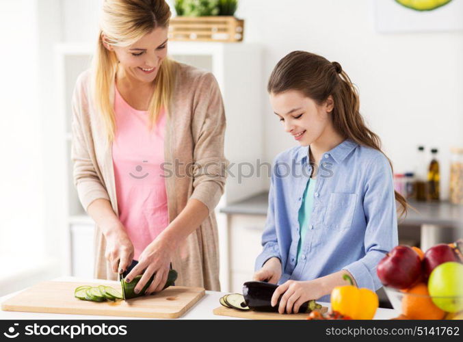cooking food, healthy eating, family and people concept - happy mother and daughter chopping vegetables for dinner at home kitchen. happy family cooking dinner at home kitchen