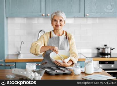 cooking food, people and culinary concept - happy smiling woman making dough or batter on kitchen at home. happy woman cooking food on kitchen at home
