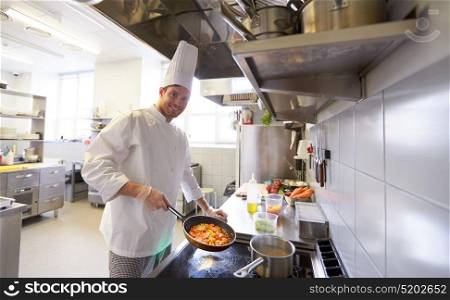 cooking food, profession and people concept - happy male chef cook with pot and frying pan at restaurant kitchen. happy male chef cooking food at restaurant kitchen