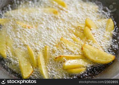 Cooking french fries or fry potatoes in hot oil for potato wedges, Close up fried potatoes in oil on pan