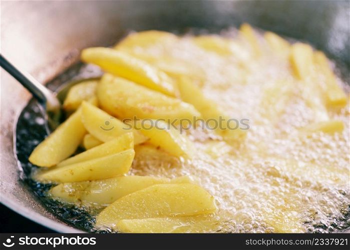 Cooking french fries or fry potatoes in hot oil for potato wedges, Close up fried potatoes in oil on pan