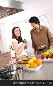 Cooking - happy couple together in modern kitchen drink red wine and cut bread
