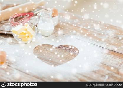 cooking, holidays, home and love concept - close up of heart of flour on wooden table