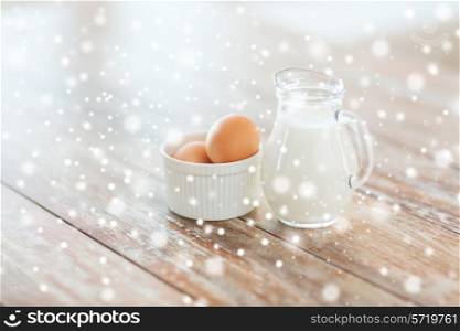 cooking, home and food concept - close up of milk jugful and eggs in bowl