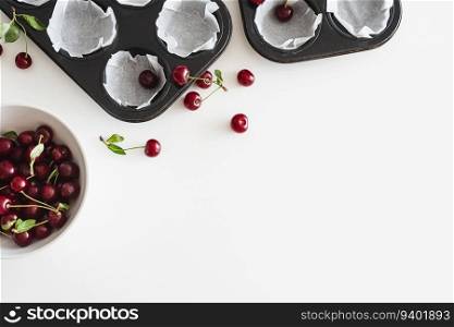 Cooking homemade cherry muffins with fresh berries on white wooden table. Top view