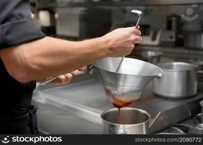 Cooking in the restaurant kitchen. Sifting sauce through a sieve. Chef is filtering sauce. High quality photo. Cooking in the restaurant kitchen. Sifting sauce through a sieve. Chef is filtering sauce.