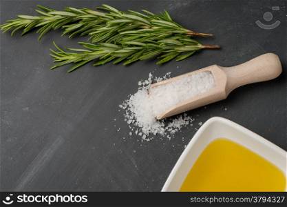 Cooking ingredients for mediterranean cuisine - olive oil, bunch of rosemary and salt.
