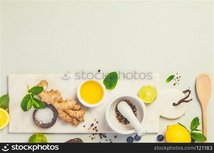 Cooking ingredients on grey concrete background: olive oil, herbs and spices. Vegan food, vegetarian and healthily cooking concept. Top view