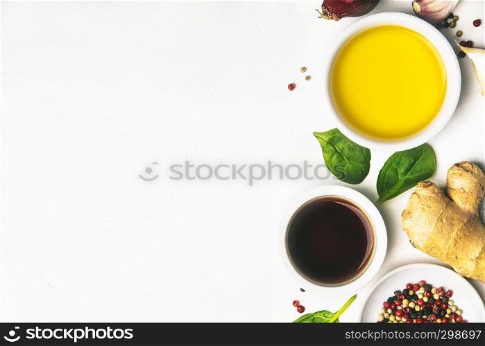 Cooking ingredients on white background: olive oil, vinegar, herbs and spices. Vegan food, vegetarian and healthily cooking concept. Top view. Olive oil, vinegar, herbs and spices, flat lay