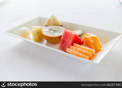 cooking, kitchen and food concept - plate of fresh juicy fruit dessert at restaurant