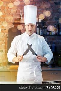 cooking, kitchenware and people concept - happy male chef cook with knife in restaurant kitchen. happy male chef cook in kitchen with knife