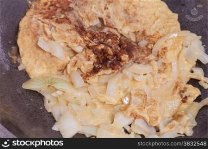 Cooking omelet and onion with hot oil in pan