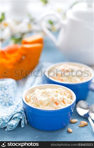 Cooking on kitchen table delicious mini casserole with cottage cheese and pumpkin for breakfast. White background