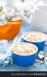 Cooking on kitchen table delicious mini casserole with cottage cheese and pumpkin for breakfast. White background
