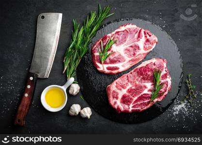 Cooking on kitchen table fresh raw pork marbled steaks on black background, top view