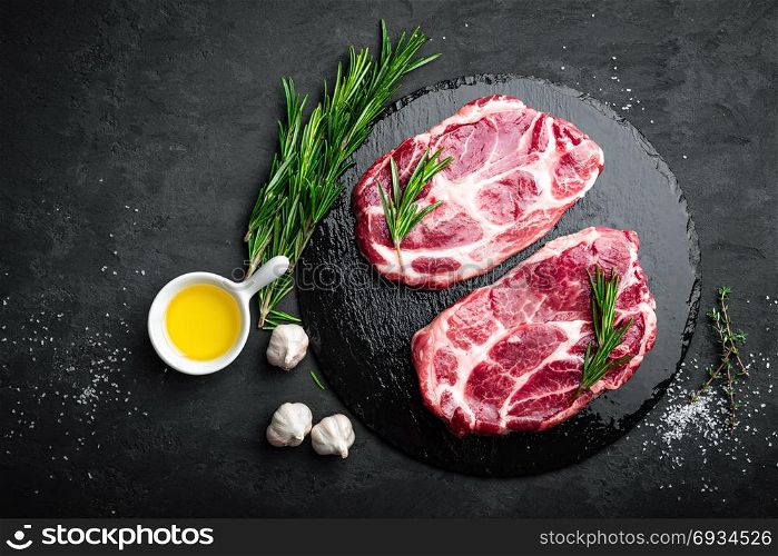 Cooking on kitchen table fresh raw pork marbled steaks on black background, top view